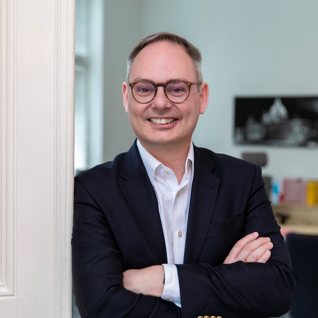Rechtsanwalt und Notar Jörgen Breckwoldt Mann in Anzug lächelt mit verschränkten Armen in einem hellen Raum.