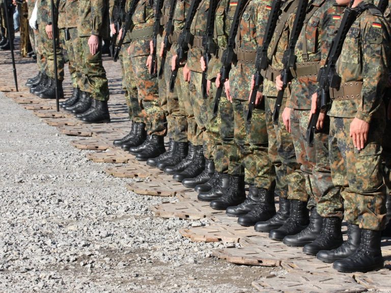 Experte für Soldatenrecht Reihe von Soldaten in Uniform, die mit festem Stand auf einem Kiesweg stehen.